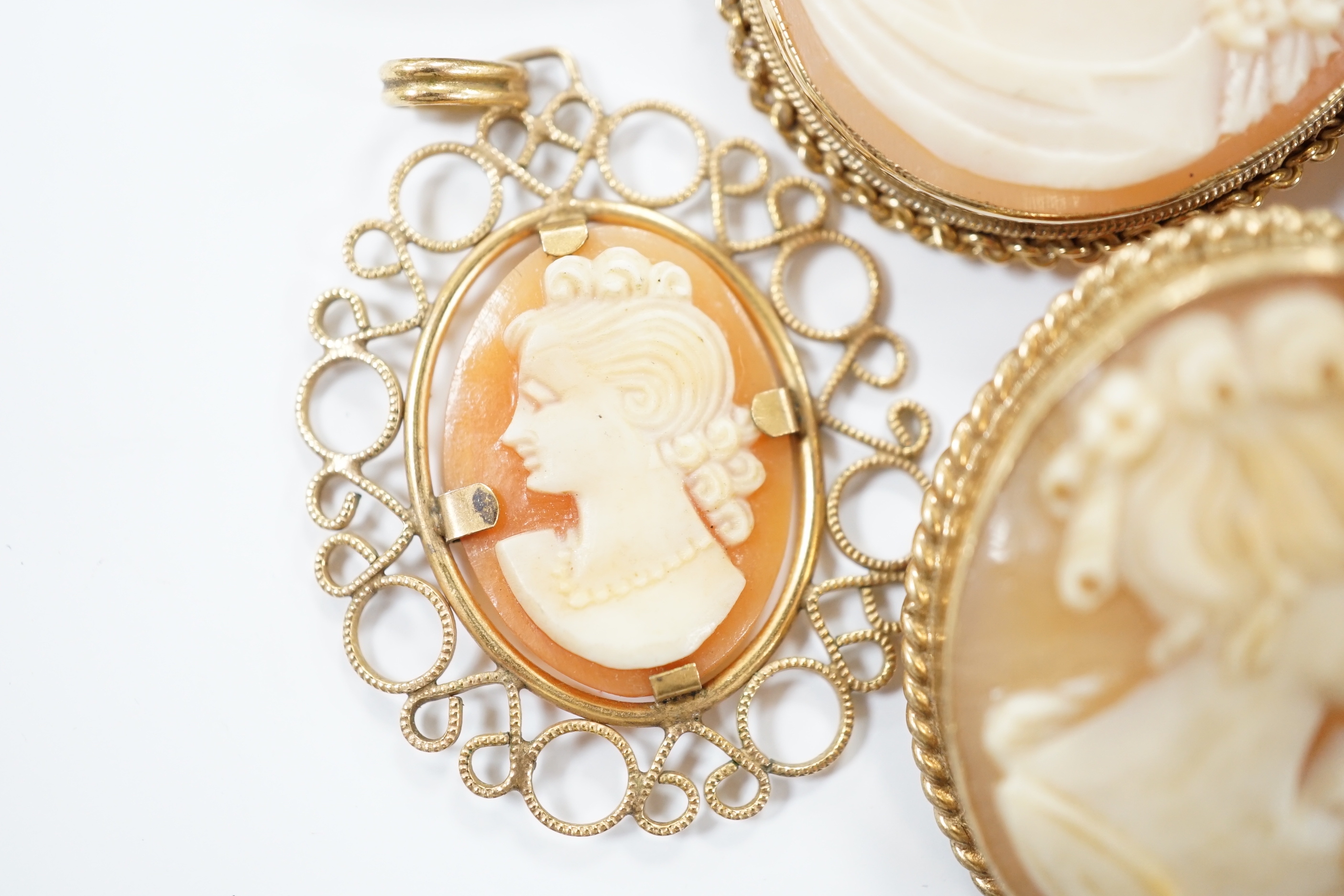 Two modern 9ct gold mounted oval cameo shell pendant brooches, largest 42cm and two other mounted oval cameo shell pendant or brooches and a mourning brooch (a,f,).